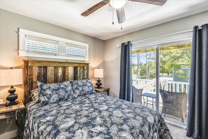 A comfortable bedroom with sliding doors leading to a balcony and a sitting area adorned with two chairs for relaxation
