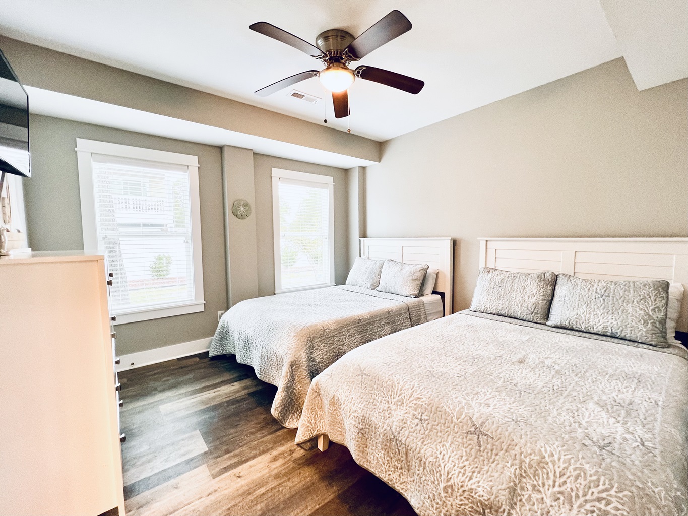 A twin bed, wooden floors, two sunny windows, and a dresser - all the comforts of home.