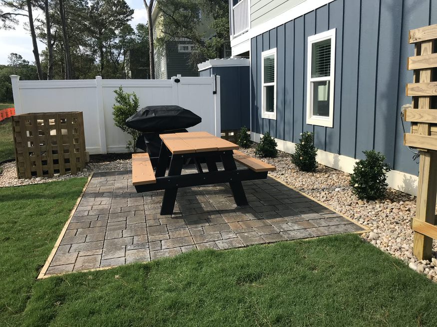 The side of the house featuring a cozy bench and a convenient BBQ grill.