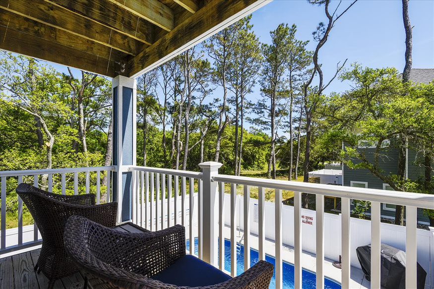 A rear deck providing a view of the house's serene backside, complete with a sparkling pool.