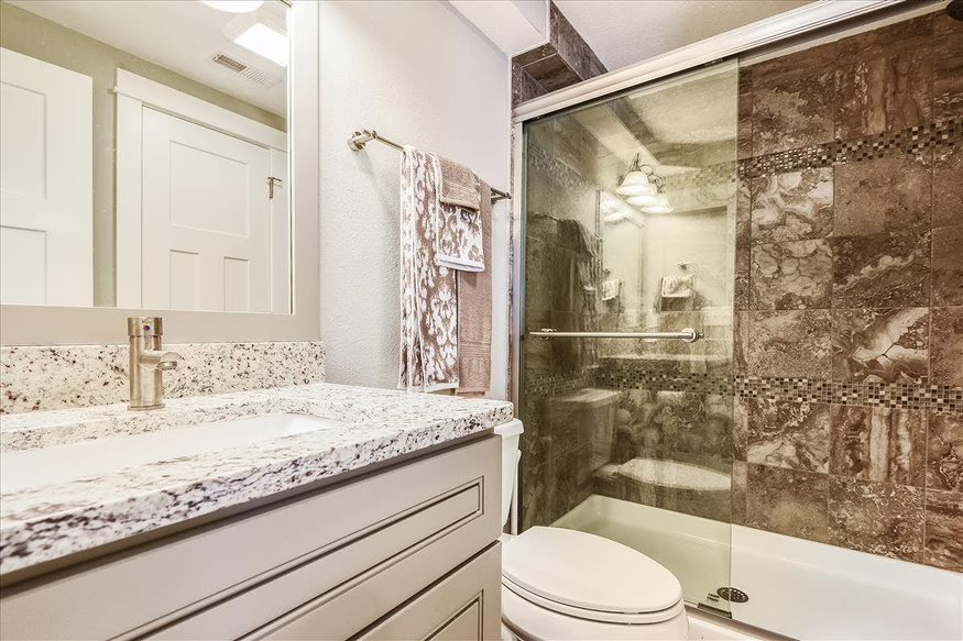 A modern bathroom with a single white-themed sink and a glass-covered shower for a clean and contemporary look.
