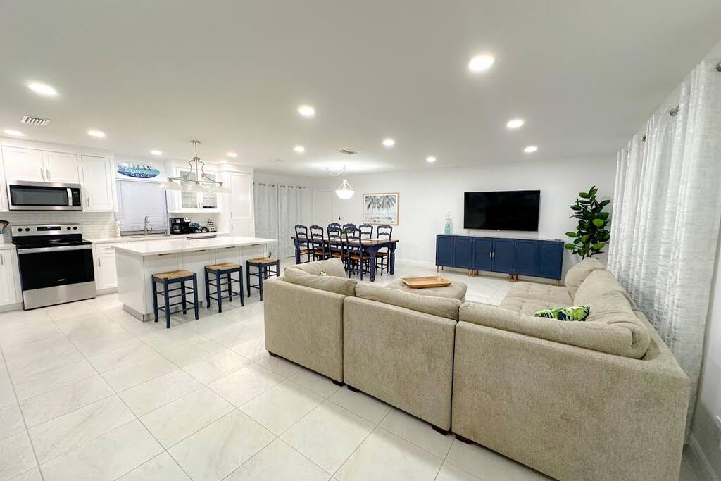 Take in the stunning view from the front entryway, where you'll find a spacious and airy living area. The open kitchen, dining area, and living room come together seamlessly, creating a large and invi - The Dolphin Retreat - Cape Coral