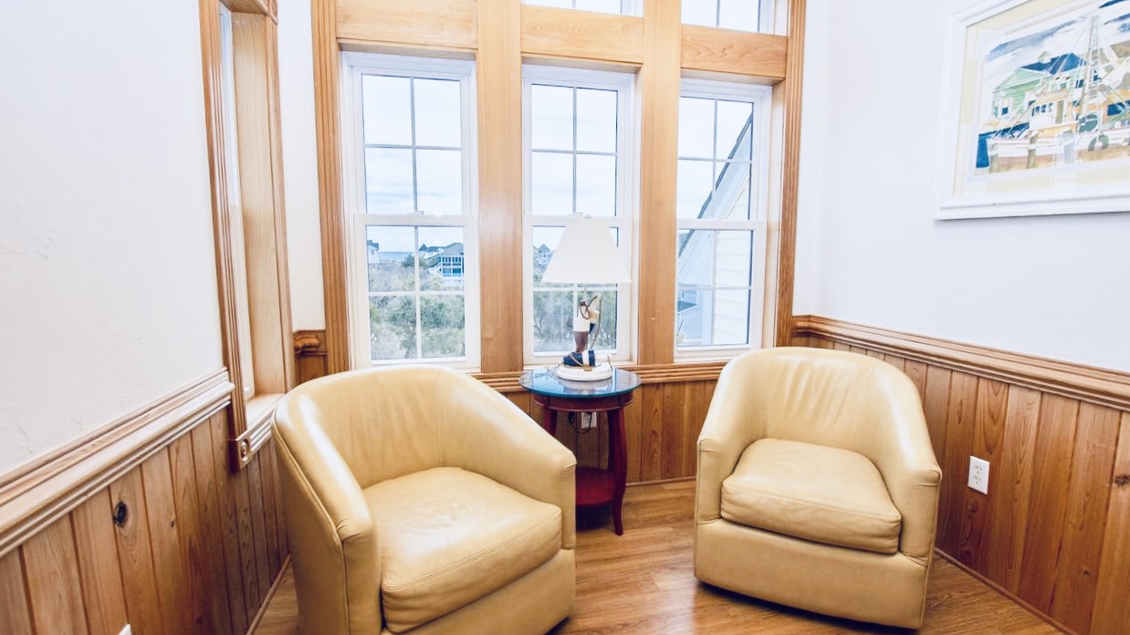 Off-white chairs by the window, with a small table.