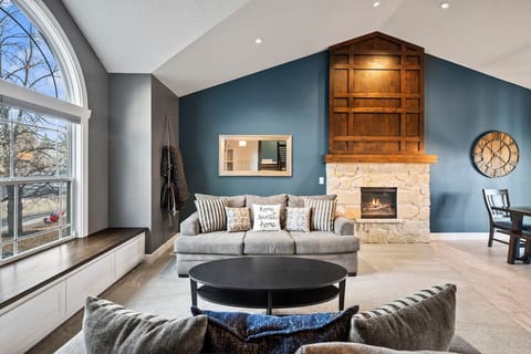 Spread out in the large, main-level living room area featuring high ceilings, an electric fireplace, and ample natural light.
