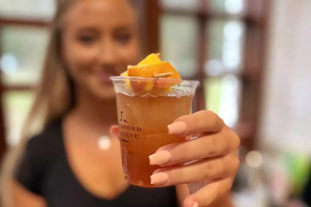 Introducing Bailey's “Porch Swing” — a beautiful refreshing cocktail featuring Woodford Reserve bourbon, lemon juice, honey, and sweet tea. Topped off with fresh peaches and a lemon wedge. Introducing Bailey's “Porch Swing” — a beautiful refreshing cocktail featuring Woodford Reserve bourbon, lemon juice, honey, and sweet tea. Topped off with fresh peaches and a lemon wedge. - Mallard Drake (Cottage #1) - Suffolk