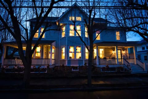 Chadwick Cottage Vacation Rental Home. Exterior at night showing Queen Anne Stained Glass Windows. Vacation Rentals Asbury Park. Vacation Rentals Ocean Grove.