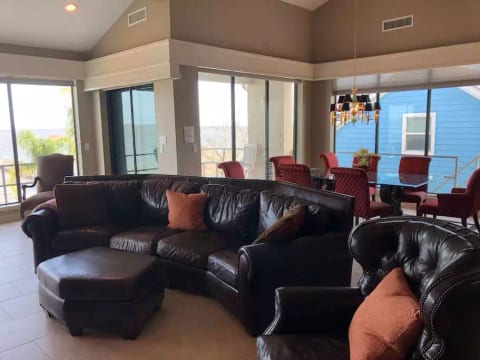 2nd Floor Living room with large couch and dining room table in background. Floor to ceiling windows provide magnificent views of the bay