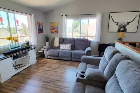 Living area with wrap-around deck and view of lake and comfortable new reclining couches with cup holders and USB chargers