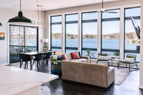 Main level living room & dining area. 12' ceilings on water side. 65" 4K HD Smart TV and gas fireplace. Walk out to screened-in porch with trex decking. Every single room and window in this house has a view of the water!