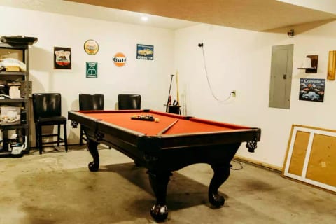 A full size pool table, foosball table, and dart board sets off the garage turned Game Room.