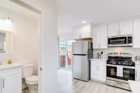 Kitchen with Full Fridge/Freezer, Range Stovetop w/ Oven, Dishwasher, Dining Counter, and Common Area Half-Bath