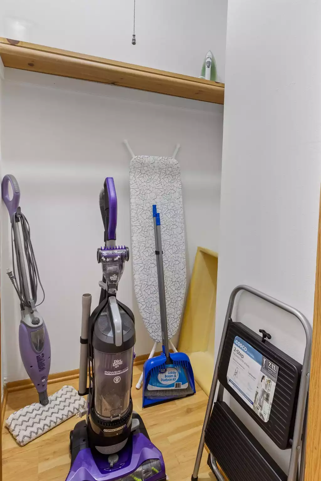 Closet with ironing board, vacuum, steam mop, broom and step stool.