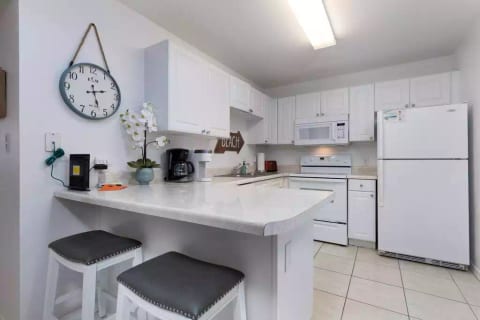 Condo 1 fully stocked kitchen with 2 stools at breakfast bar.