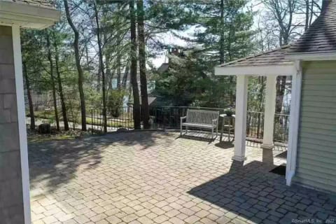 Upper patio. The game building (former garage) is on the left, the main entry to the house is to the left of the bench and table.