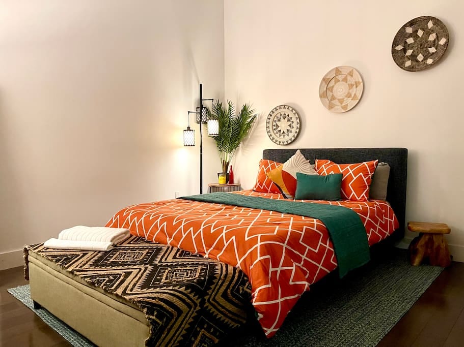 Queen size bed with dresser and and clothing rack.
