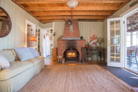 The living room opens up to a larger screened-in porch. Dining also on the porch. It features a wood-burning fireplace for cooler times. It will be all set to light and we provide plenty of wood.