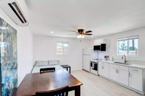 Open Studio Layout with Full Size (Double) Bed, Mounted 55" Roku TV, Full Fridge/Freezer, Mini 24" Range Stovetop w/ Oven, Microwave, and Dining Table w/ Chairs.