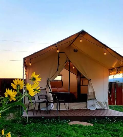 View of the Zinnia Glamping Tent in the evening, with a covered porch and sitting area.