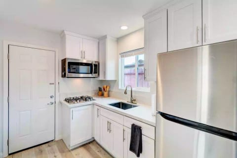 Open Concept Kitchen with Full Fridge/Freezer, Range Stovetop (Stove Only, NO OVEN), Air Conditioning (AC), Dining Table, 55" Wall Mounted Roku TV, Sofa (converts flat to full size bed) and Common Area Half-Bath