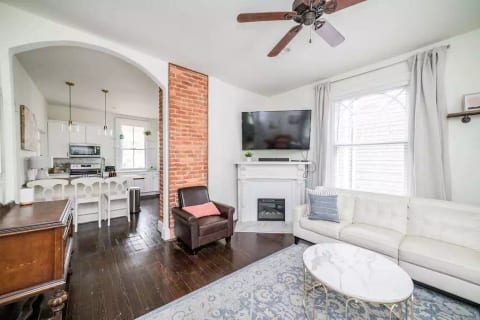 Living room looking into kitchen. 65 inch tv and exposed brick chimney.