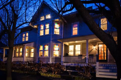 Chadwick Cottage Vacation Rental Home. Exterior at night showing Queen Anne Stained Glass Windows. Vacation Rentals Asbury Park. Vacation Rentals Ocean Grove.