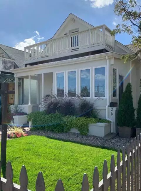 Private 2 story house on corner with picket fence.