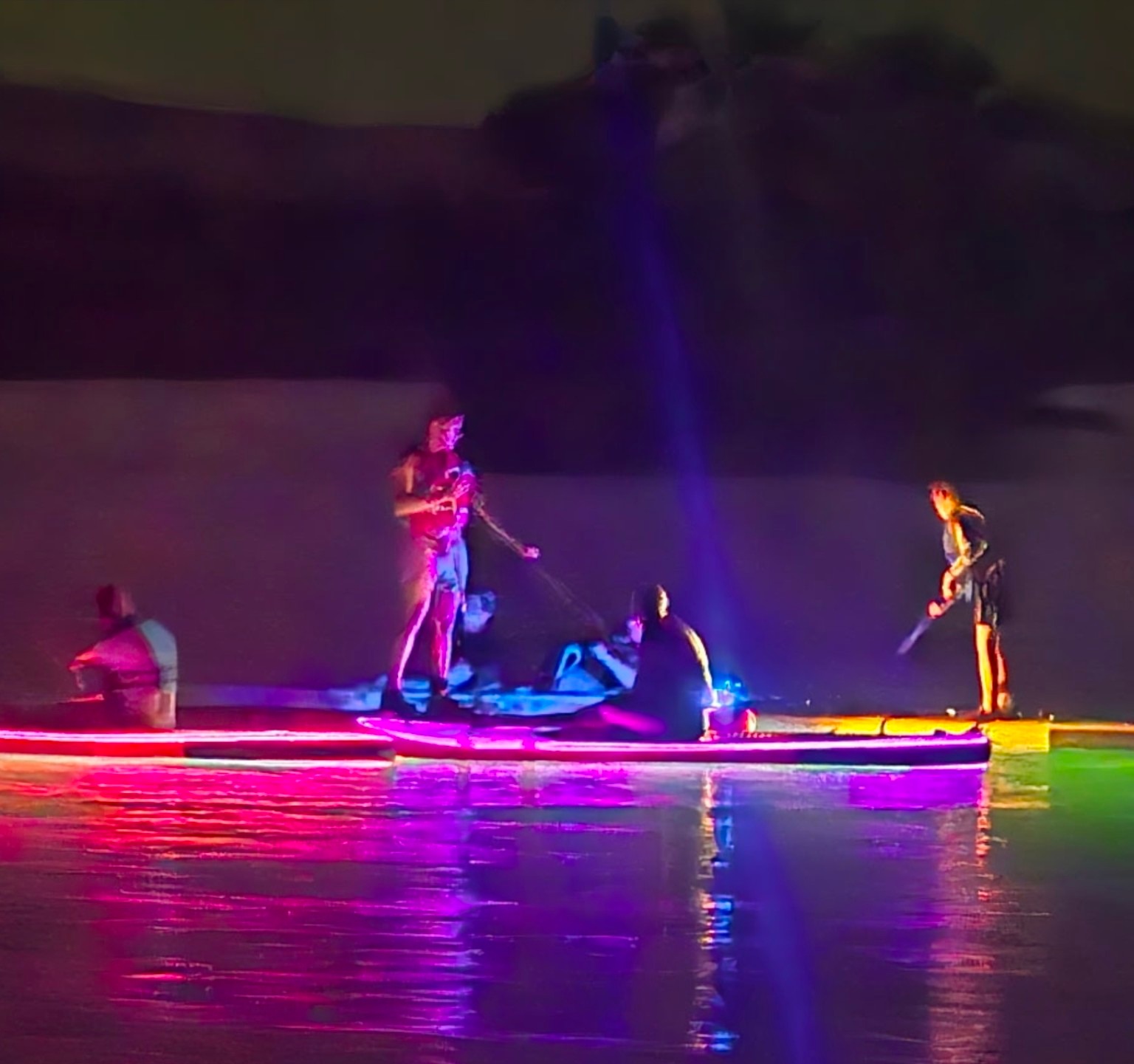Guests on colorful light up GLO Boards after dark